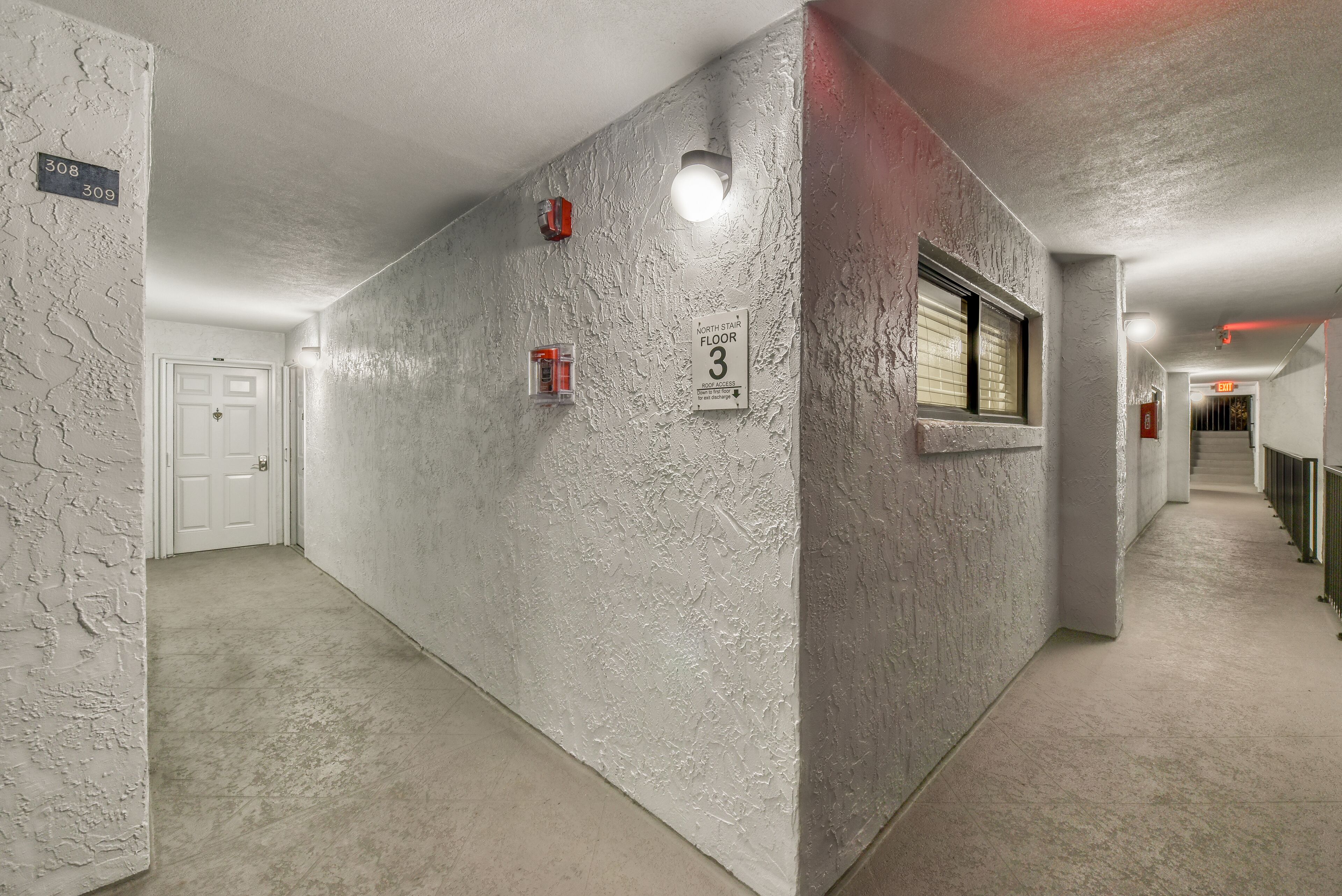Ein Korridor mit strukturierter Wandgestaltung, einer Tür und einem Schild, das 'Nordtreppe 3. Etage Zugang zum Dach' anzeigt.