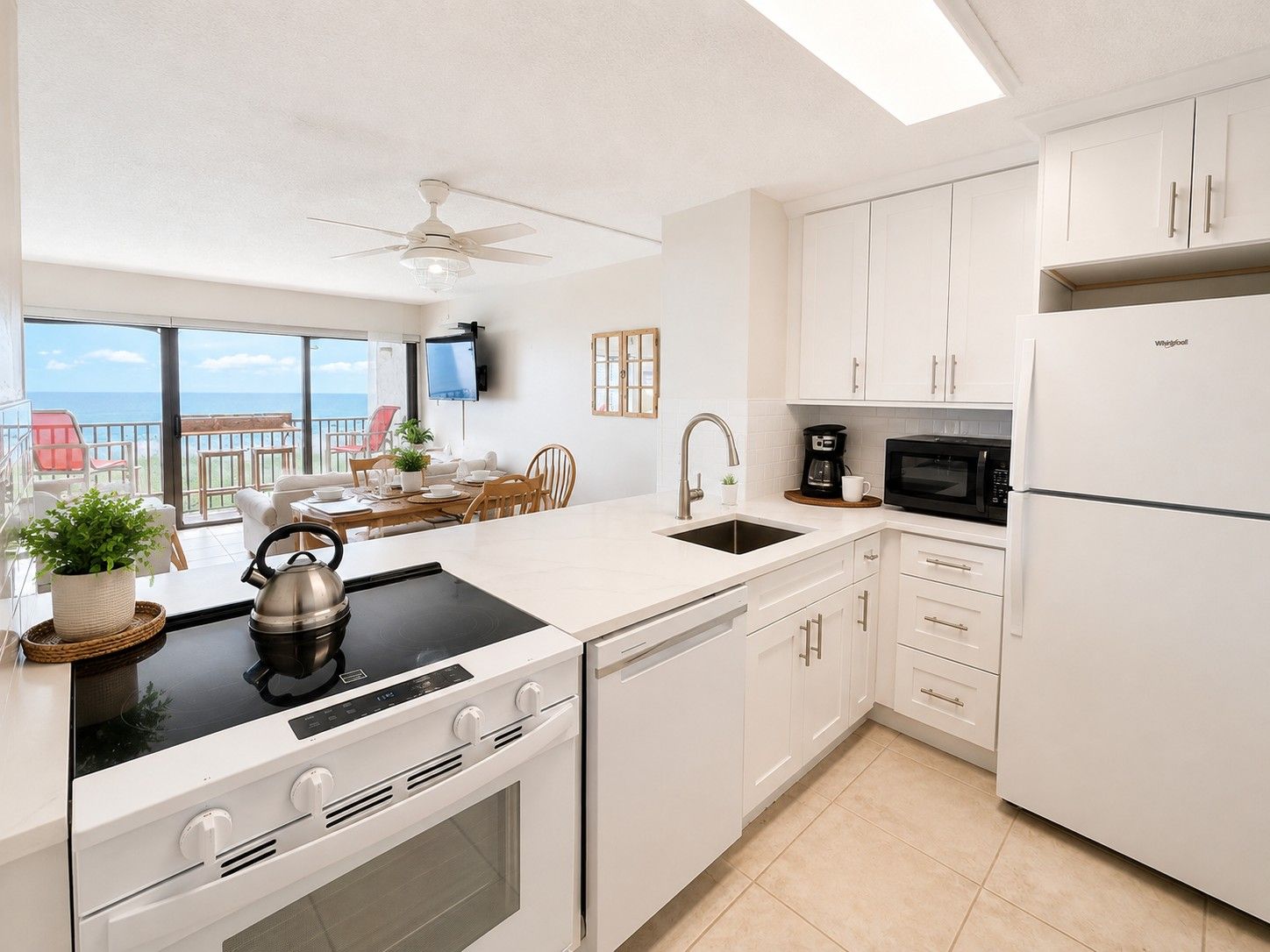 A modern kitchen with white cabinetry, a built-in oven, a microwave, and a sink.