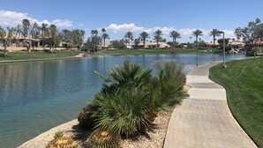 Un parcours de golf avec un étang, des palmiers et un ciel bleu azur.