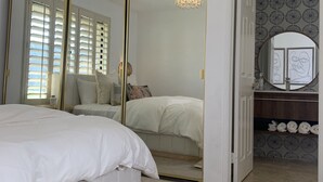 Une chambre à coucher avec un grand lit, un miroir et un lustre.