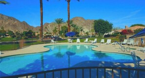 A swimming pool with lounge chairs and palm trees.