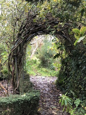 Un arco de piedra natural en un área boscosa, con un sendero que lo atraviesa.