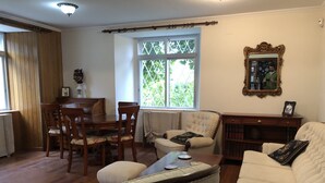 Ein Wohnzimmer mit Essbereich, einem großen Fenster mit Aussicht, einem Spiegel und einem Bücherregal.