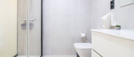 Chuveiro, secador de cabelo, toalhas de banho, papel higiênico