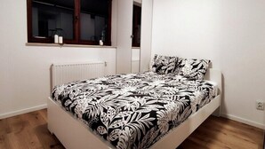 A bedroom with a bed, a window with blinds, a radiator, and a mirror. - Unique Apartment With Amazing 90 m² Roof Terrace (Wroclaw)