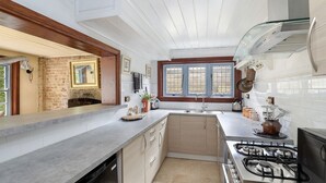 A modern kitchen with a central island, a gas stove, and a window with multiple panes.