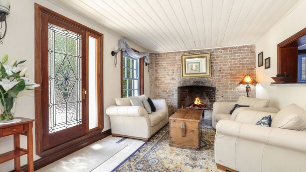 A cozy living room with a fireplace, two white sofas, a wooden coffee table, and a patterned rug.