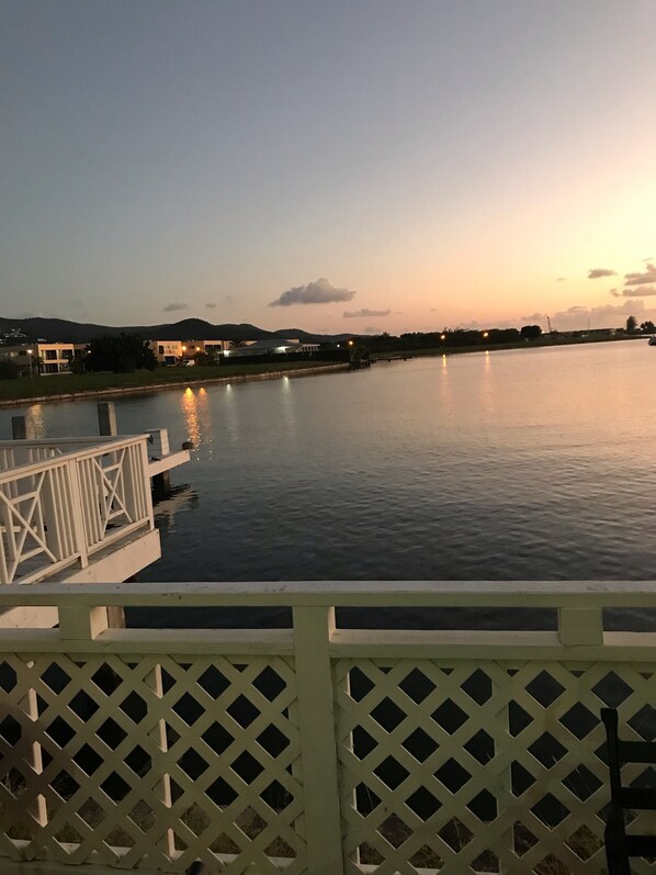 Un río tranquilo al anochecer con un muelle de madera y una valla blanca.