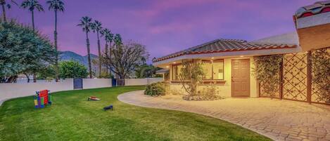 A residential property with a well-maintained lawn, a patio area, and a house with a tiled roof.