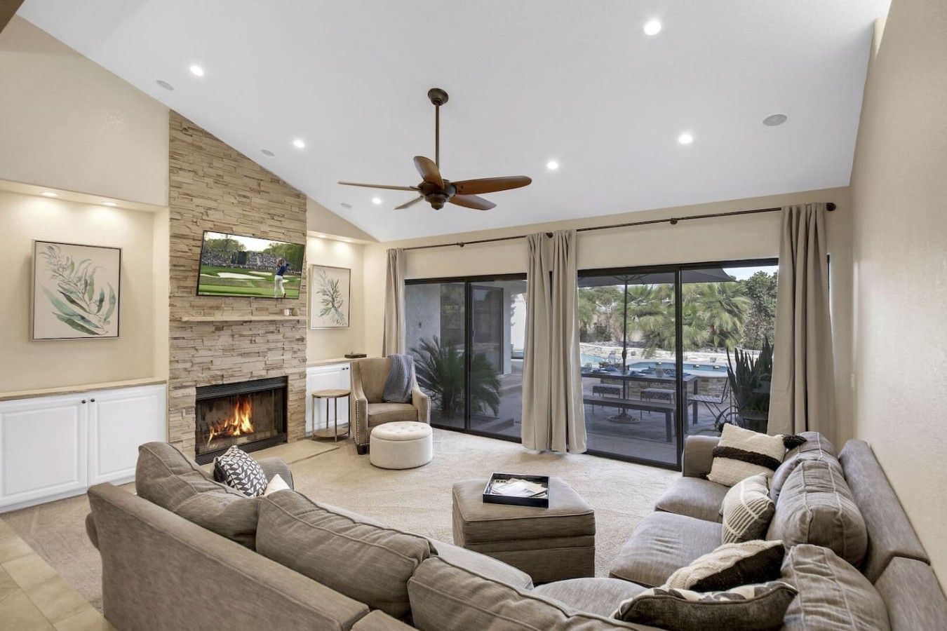 A spacious living room with a fireplace, comfortable seating, a ceiling fan, and a large sliding glass door leading to an outdoor area.