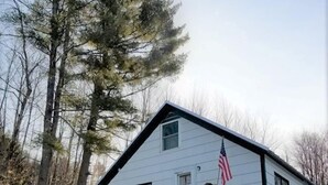 A two-story house with a wooden deck and a stone wall in front.