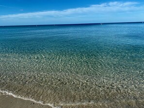 A clear view of a beach with shallow water and a distant horizon.