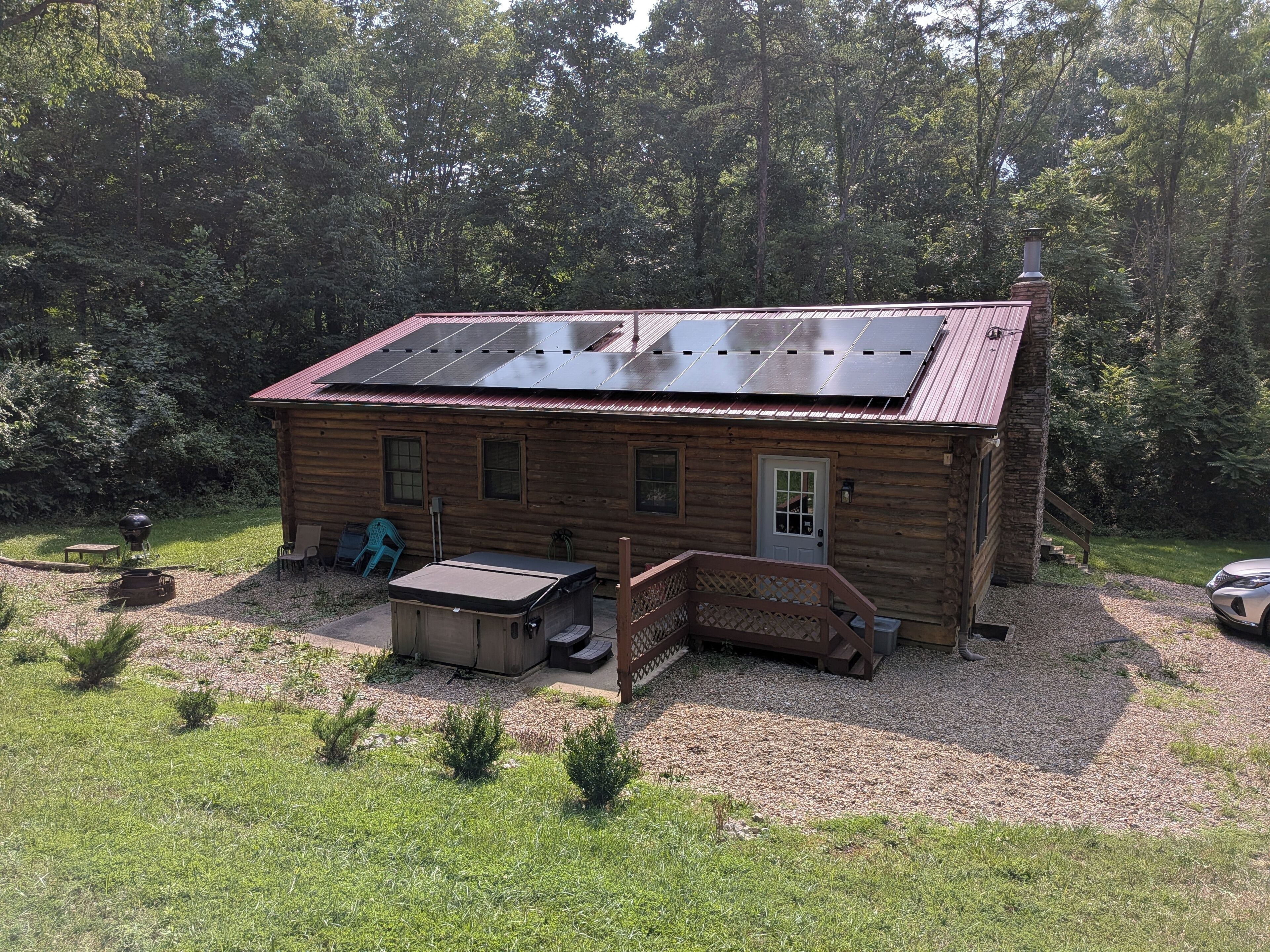 Een houten chalet met een zonnepaneel dak, een veranda en een grindpad.