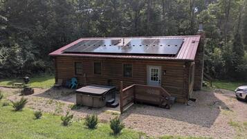 Een houten chalet met een zonnepaneel dak, een veranda en een grindpad.