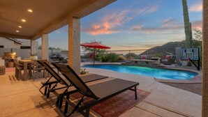 An outdoor pool area with lounge chairs, a dining table, and a red umbrella. - Incredible golf course views with modern, southwest inspired decor (Mesa)