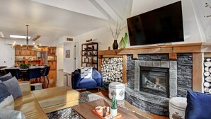 A modern living room with a fireplace, a dining area, and a kitchen. - Mistaya Suite | Stylish Downtown Penthouse (Canmore)