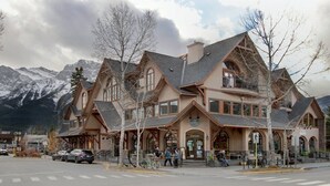 A large, multi-story building with a traditional architectural style, featuring prominent wooden beams and a symmetrical facade. - Mistaya Suite | Stylish Downtown Penthouse (Canmore)