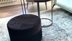 A living room with a round black ottoman, a round wooden table with two white cups, a grey sofa, and a light blue couch. - Exclusive housing in the center of Burgos. (Burgos)