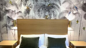 A bedroom with a wooden headboard, two green pillows, white sheets, and a patterned wall. - Exclusive housing in the center of Burgos. (Burgos)