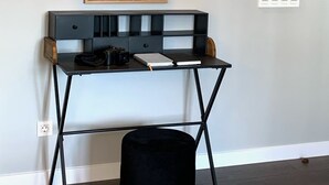 A room with a desk, a black ottoman, and a painting on the wall. - Exclusive housing in the center of Burgos. (Burgos)