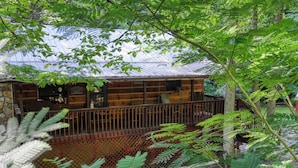 Eine rustikale Holzhütte mit einer Holzterrasse und einer überdachten Sitzgelegenheit im Freien.