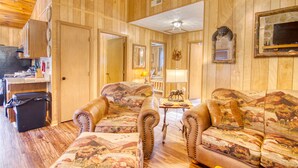 Ein Zimmer mit Holzvertäfelung, einer Sofagarnitur, einem kleinen Tisch und einem Fernseher.