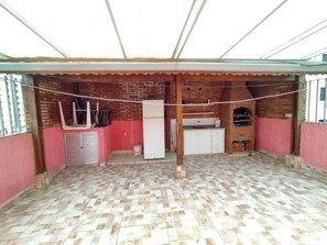Uma cozinha com piso ladrilhado, geladeira e pia.