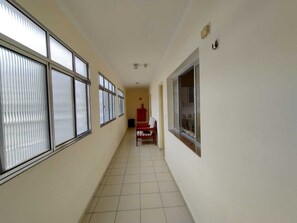 Um corredor com janelas amplas de um lado e uma porta no fim.