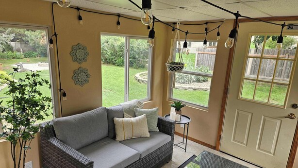 A cozy living room with a grey sofa, a small side table, and a potted plant.