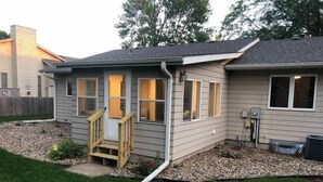 A house with a covered porch, a small set of stairs, and a window with a view of the backyard.