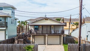 Une maison à deux étages avec un balcon, un garage et une cour arrière clôturée.