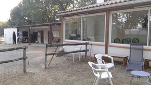 Een rustieke buitenruimte met houten omheining, een tafeltje en twee stoelen.