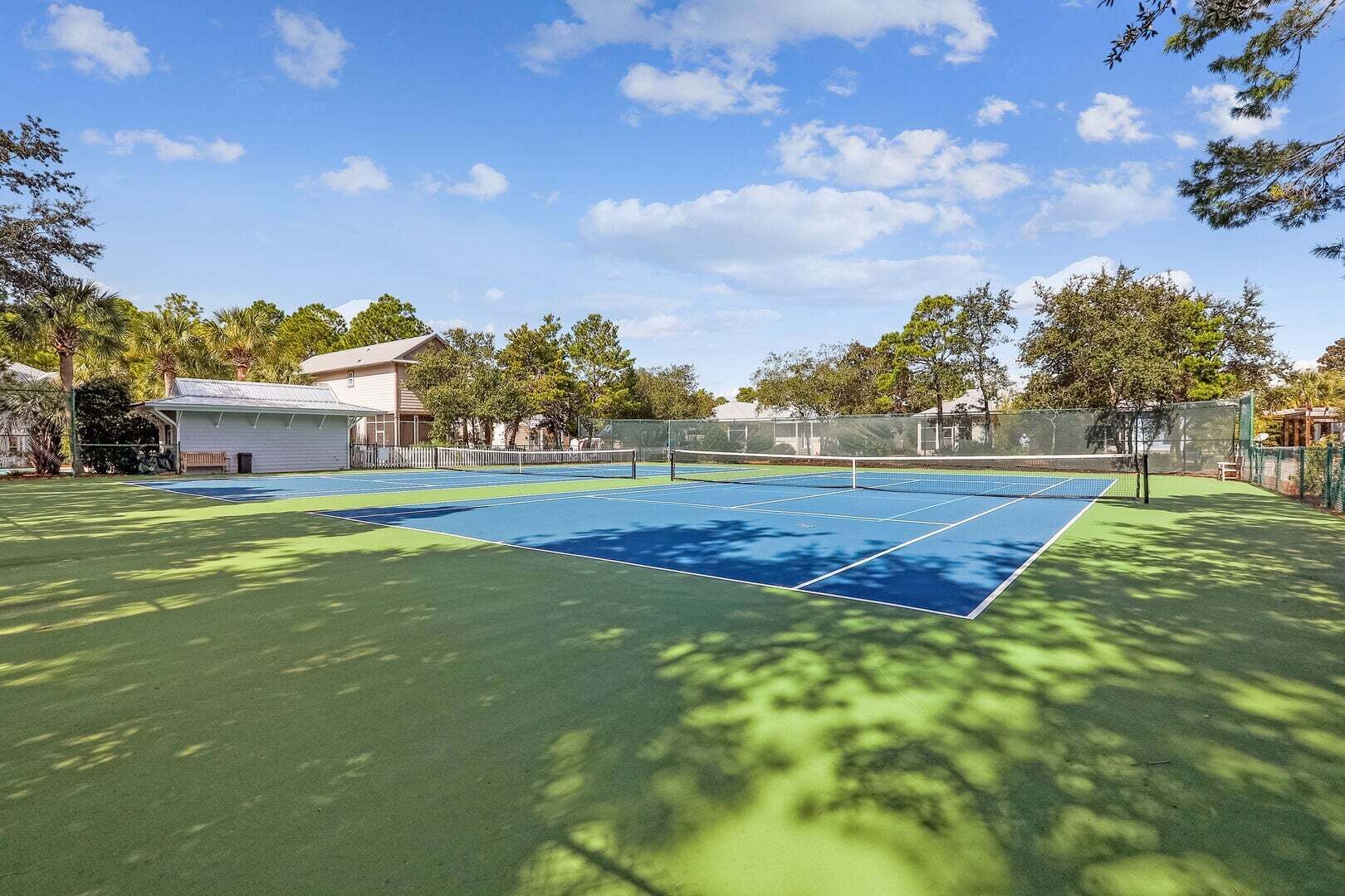 A tennis court with a net, surrounded by trees and a building.