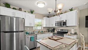 A modern kitchen with white cabinets, stainless steel appliances, and a central island. - Hidden gem just a drive from the beach and village (Merritt Island)