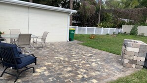 A patio area with a brick floor, outdoor furniture, and a white fence in the background. - Hidden gem just a drive from the beach and village (Merritt Island)