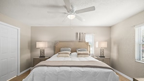 A bedroom with a bed, bedside tables, a ceiling fan, and a window with blinds. - Hidden gem just a drive from the beach and village (Merritt Island)
