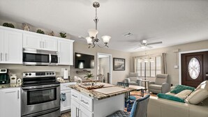 A modern kitchen with white cabinets, a stainless steel oven, and a central island with seating. - Hidden gem just a drive from the beach and village (Merritt Island)