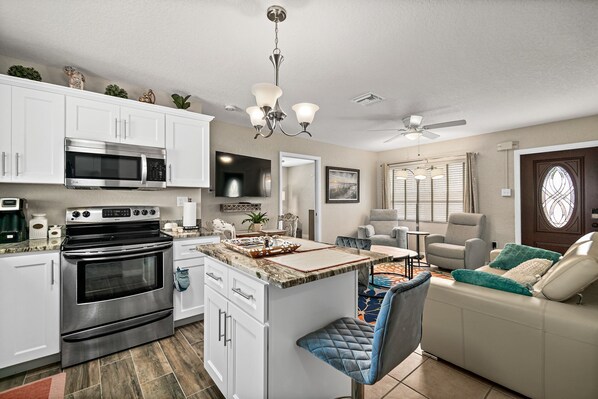 A modern kitchen with white cabinets, a stainless steel oven, and a central island with seating.