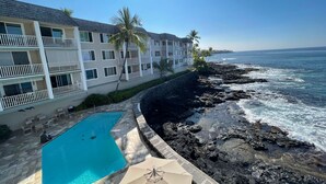 A beachfront hotel with a swimming pool, balconies, and a view of the ocean. - Hale Kona Kai 312 - Absolute Oceanfront Condo with wraparound lanai (Kailua Kona)
