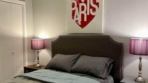 Ein Schlafzimmer mit einem Bett, zwei Nachttischlampen, einem Deckenventilator und einer Wand mit dem Schriftzug 'PARIS'.