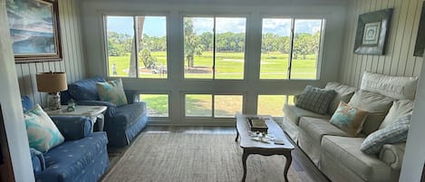 A living room with a large window, a ceiling fan, and two sofas.