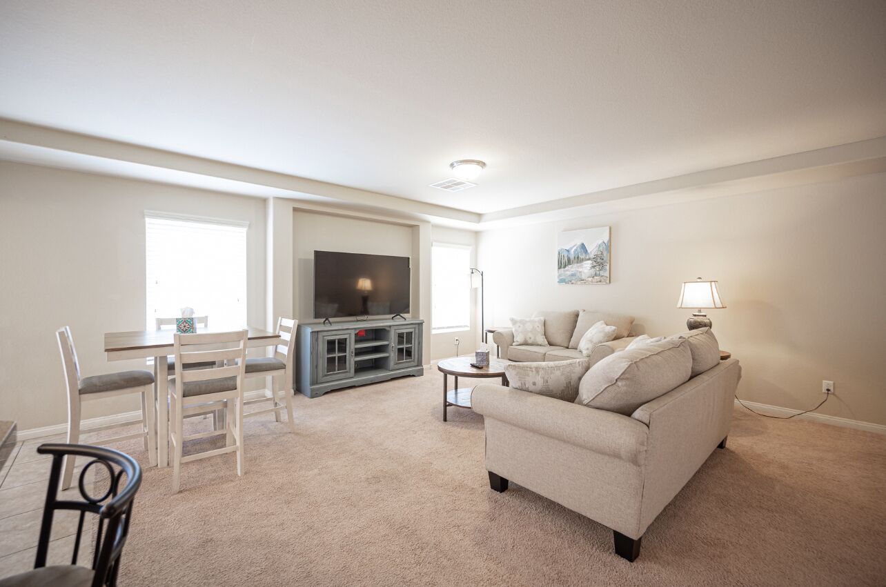 A living room with a TV, sofa, and dining area.