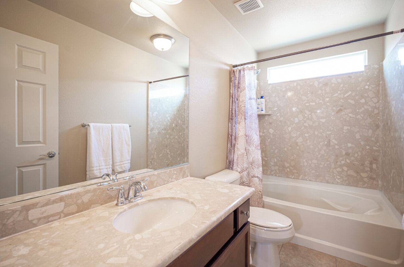 A bathroom with a sink, mirror, toilet, and bathtub.