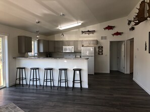 A modern kitchen with a central island, bar stools, a microwave, and a refrigerator. - LOCATED ON THE KENAI RIVER!! Kenai River Haven Unit #4. (Soldotna)