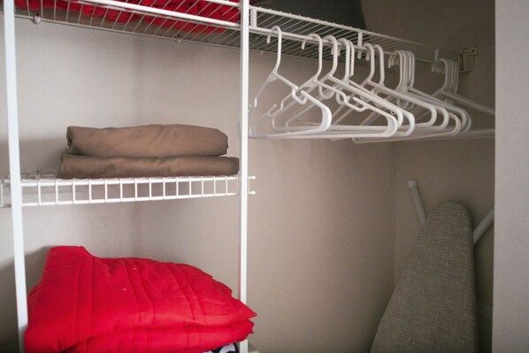 A closet with shelves, a red item, and white hangers.