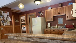 Una cocina con encimeras de granito, armarios de madera, un refrigerador y un comedor con sillas.