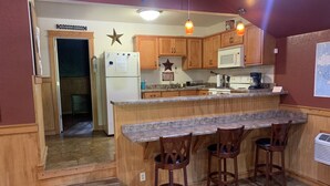 Una cocina con armarios de madera, encimera de granito y una zona con taburetes de bar.