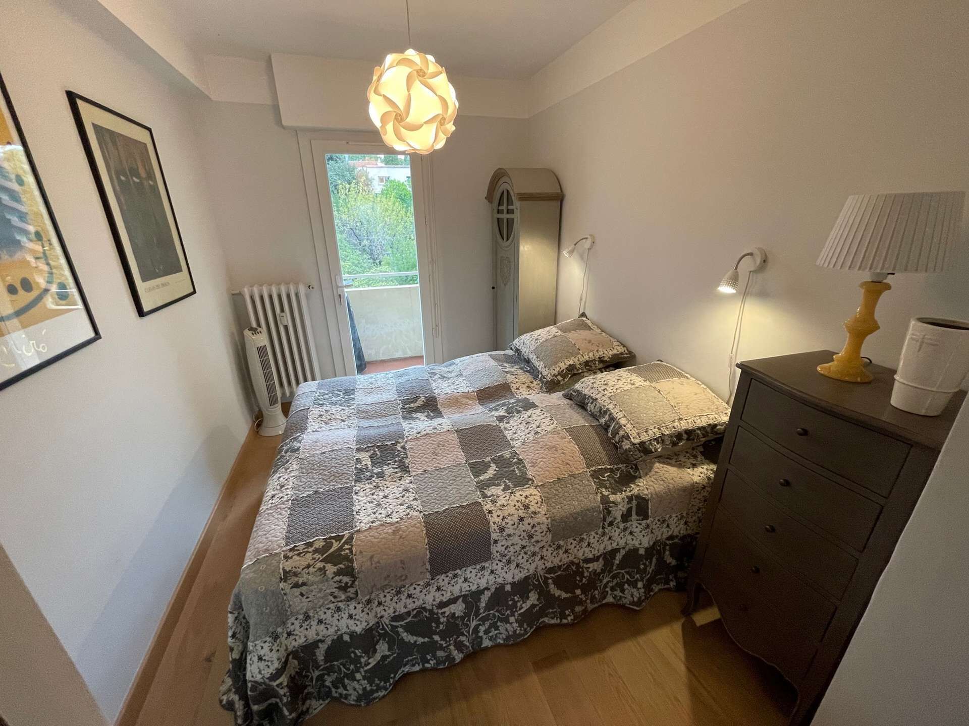 Ein Schlafzimmer mit Bett, Schminktisch, Heizkörper, Fenster und Tür.