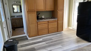 Una cocina con armarios de madera, encimera de granito y refrigerador negro.