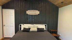 Un dormitorio con cama, techo de madera, una puerta y un cartel en la pared.